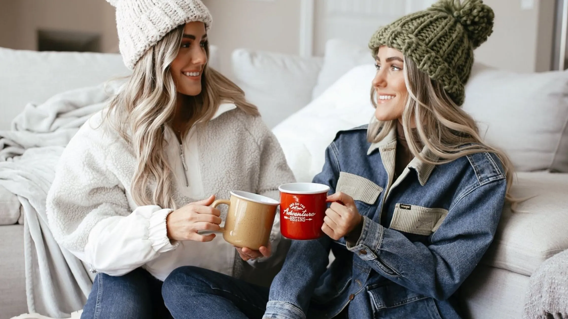 two women in knit hats holding coffee cups