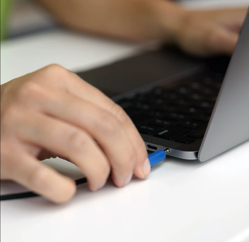 a hand holding a blue pen to a laptop