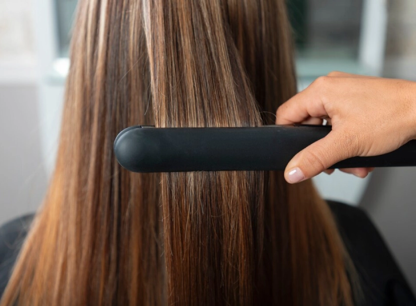 a person brushing hair with a black hair iron