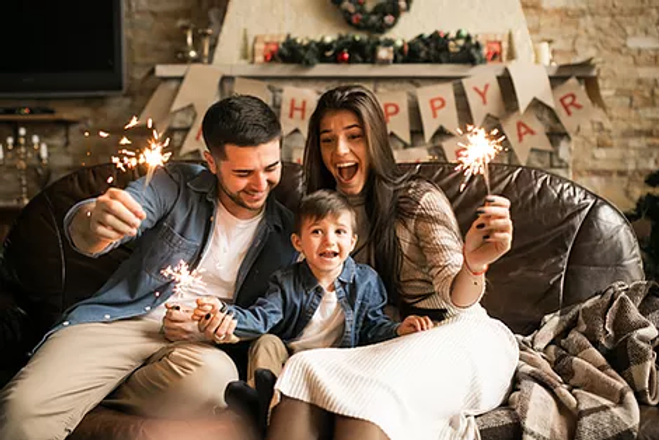 a family sitting on a couch holding sparklers