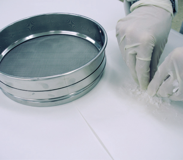 a person putting powder into a sieve