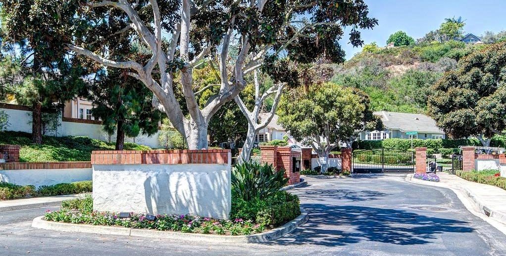 a driveway with trees and a white wall