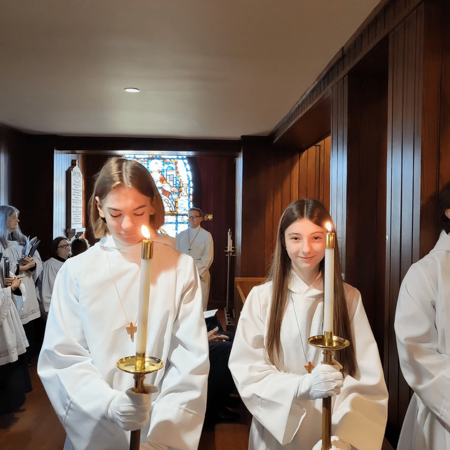 a group of girls in white robes holding candles