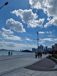 a group of people walking on a sidewalk by the water