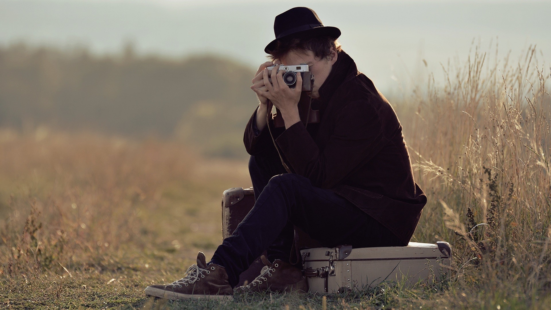 a man sitting on a suitcase holding a camera