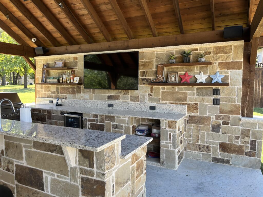 a stone bar with a television and a mirror