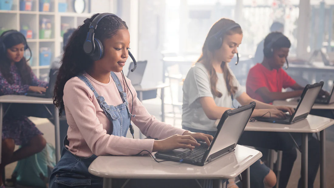 a group of people sitting at desks with headsets on their laptop