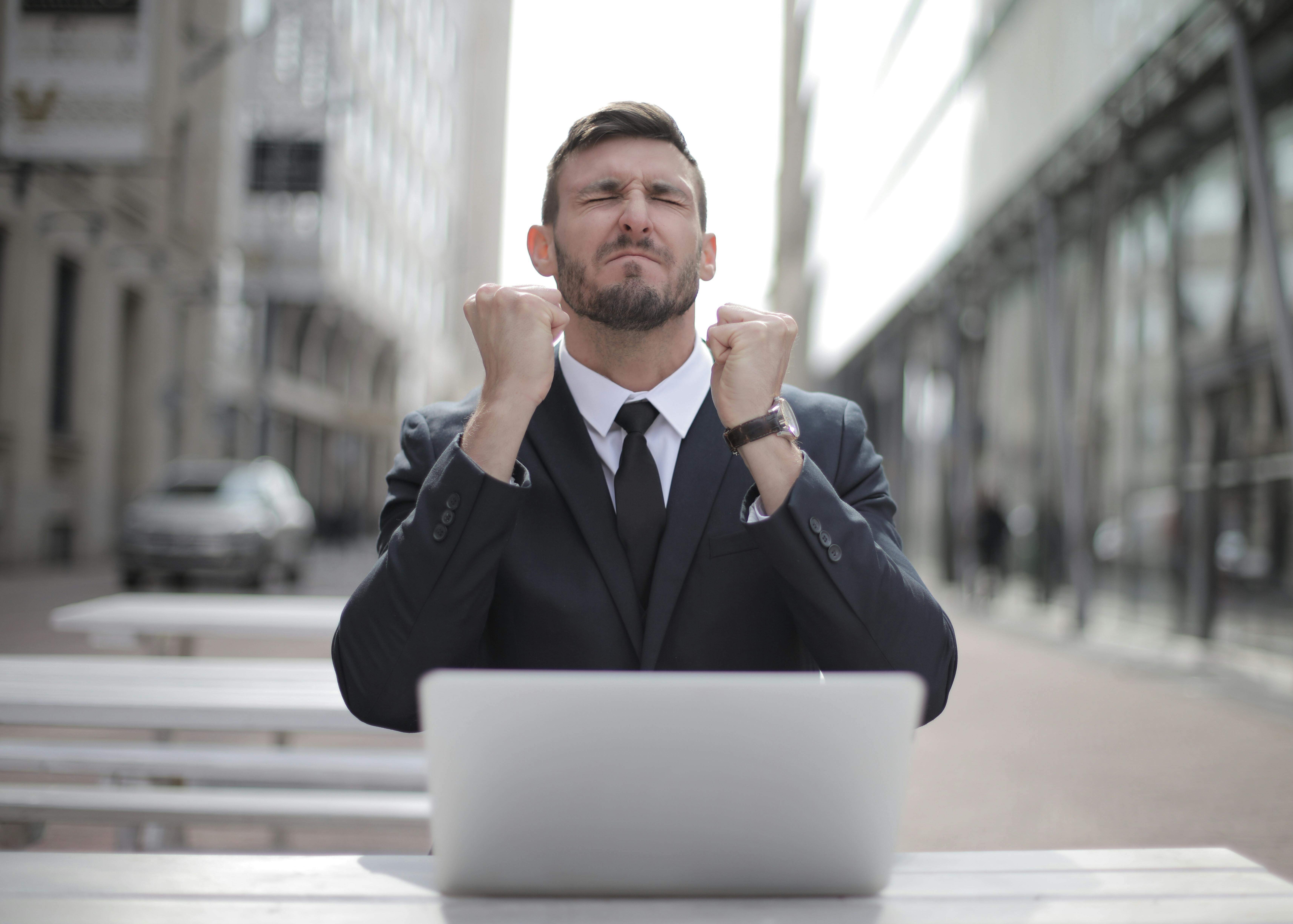 a man in a suit and tie with his hands up in front of a laptop