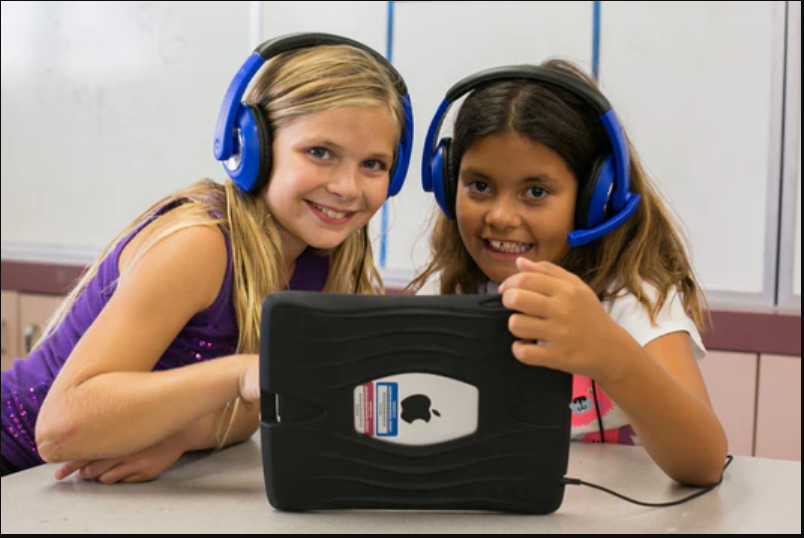 a couple of girls wearing headphones and looking at a tablet