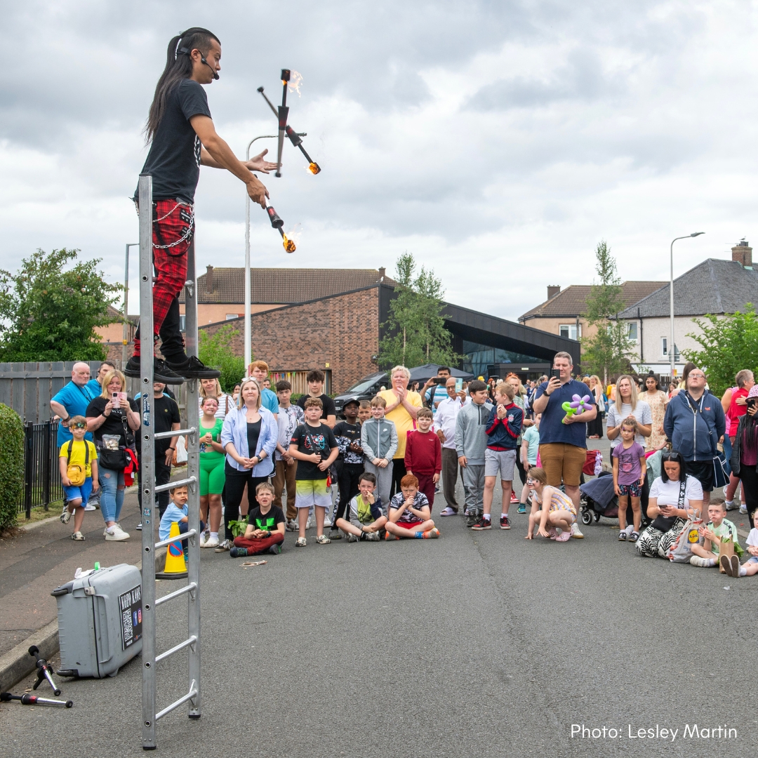 a man on a ladder juggling with a crowd of people