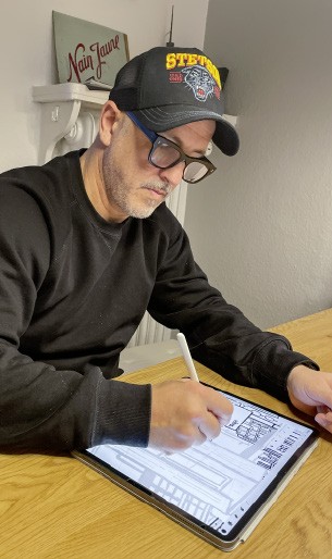 a man wearing glasses and a hat writing on a tablet