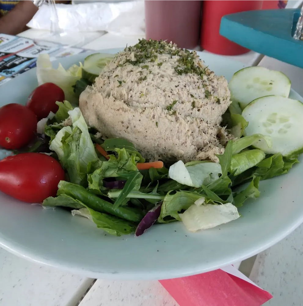 a plate of salad with a hummus and vegetables