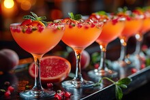 a row of glasses with orange liquid and fruit