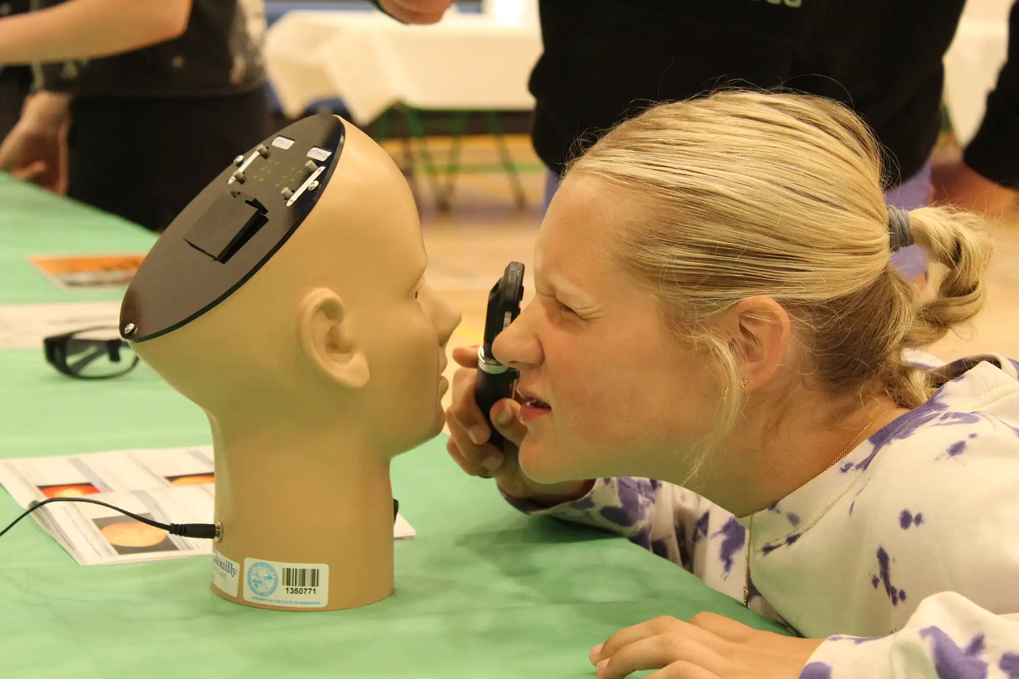 a woman using a magnifying glass to look at a mannequin head