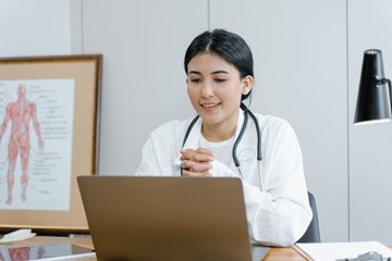 a woman in a white coat looking at a laptop