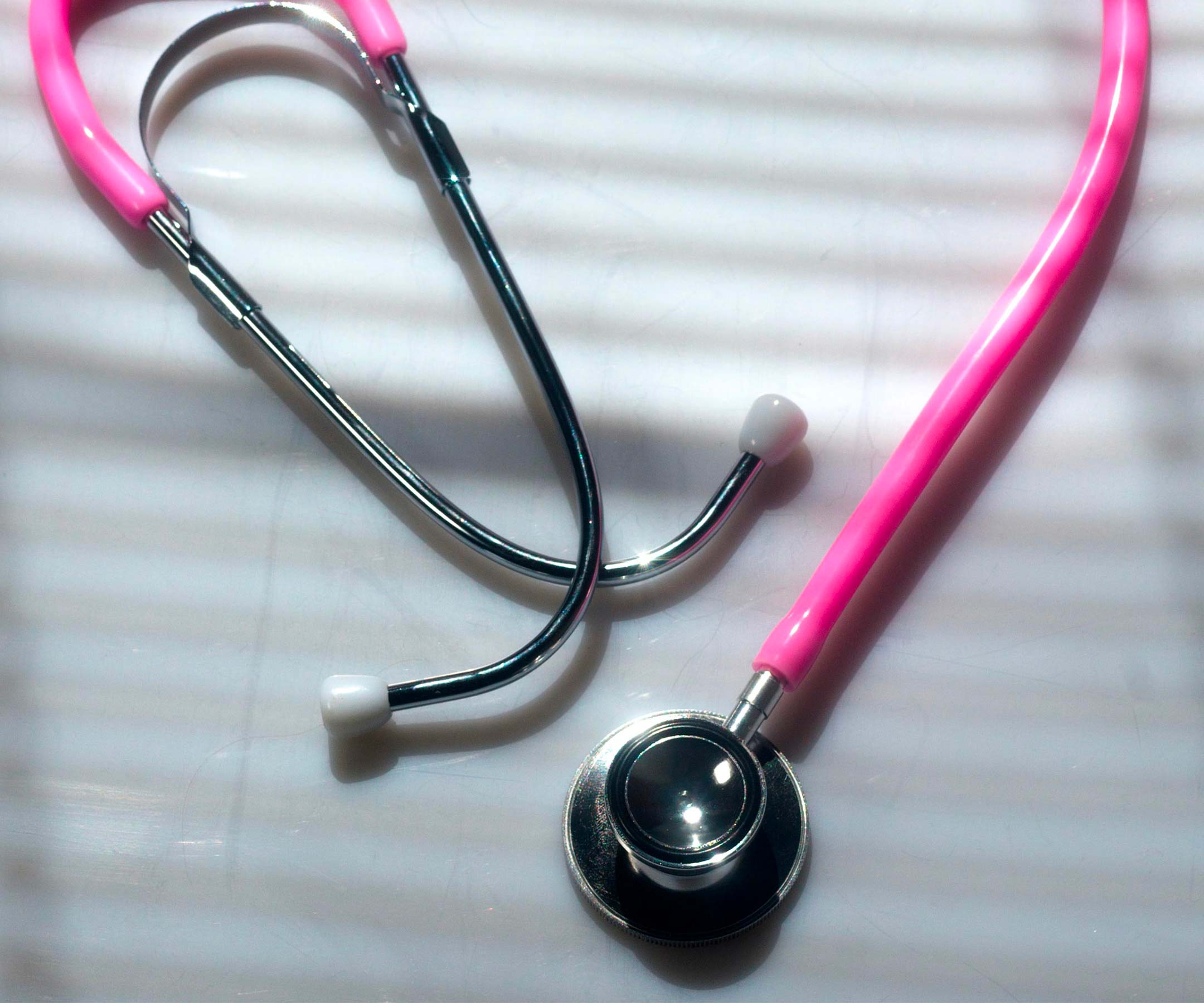 a pink stethoscope on a white surface