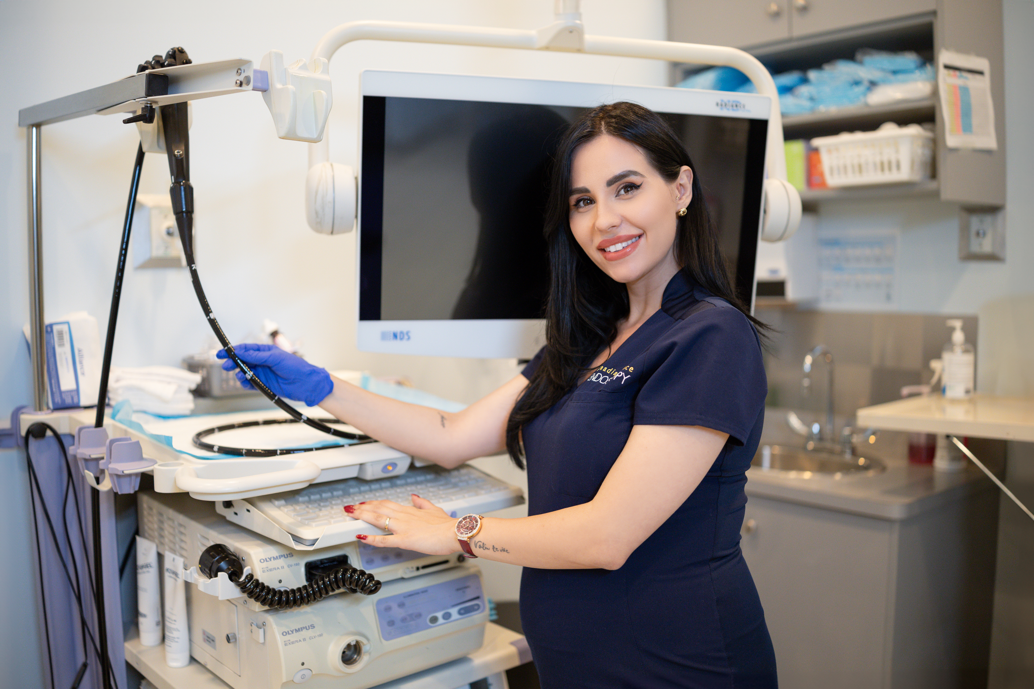 a woman in blue scrubs standing in front of a computer