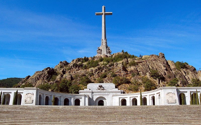 a large cross on top of a hill with Ibrahim-al-Ibrahim Mosque in the background