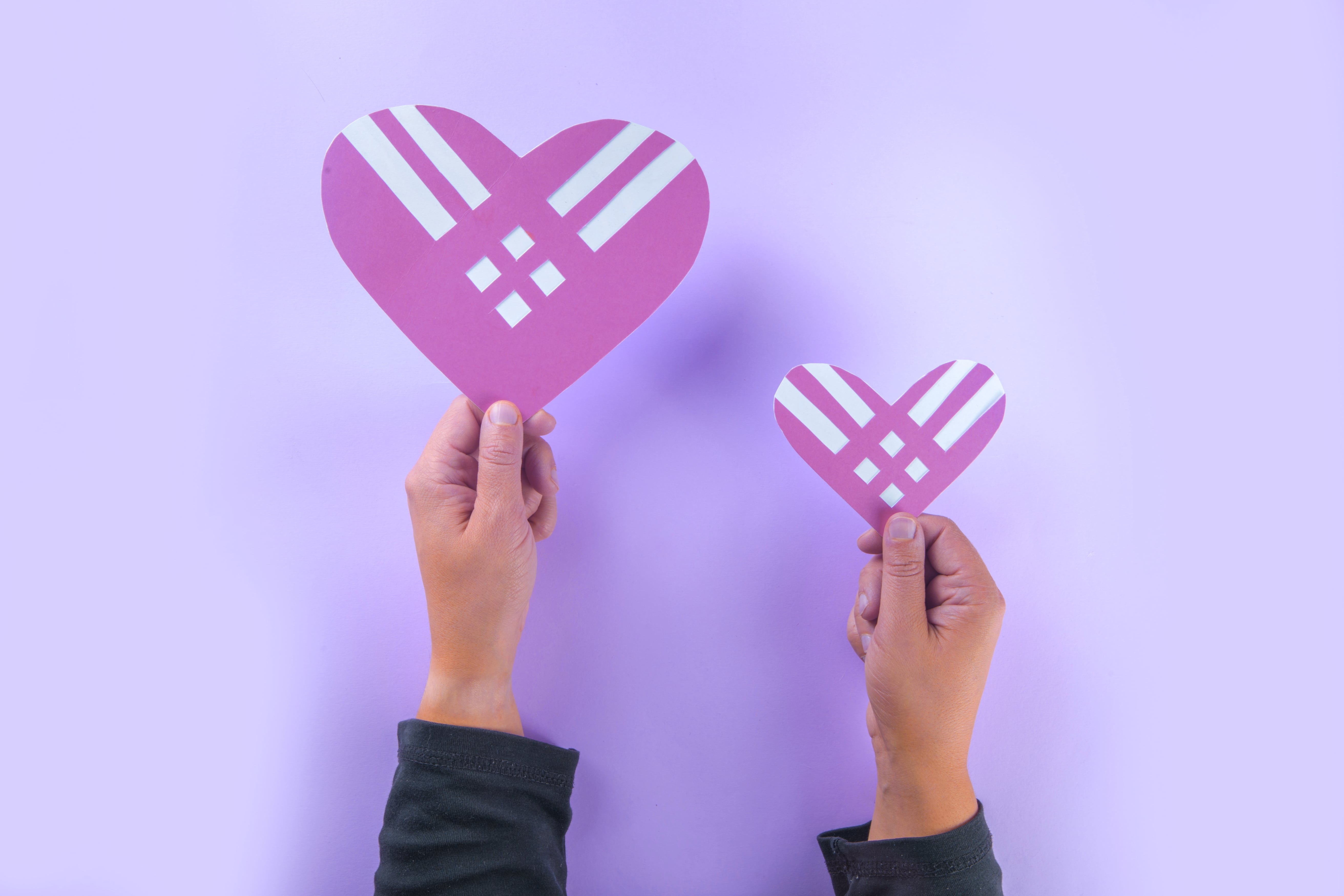 a pair of hands holding up a heart shaped paper