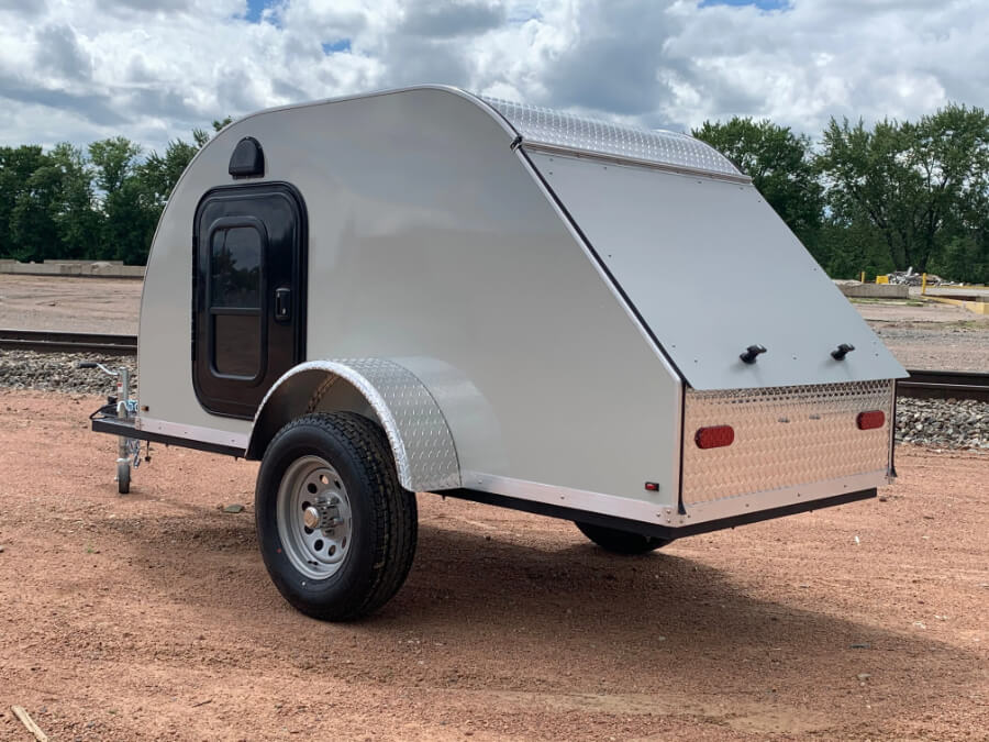 a silver trailer on a dirt road