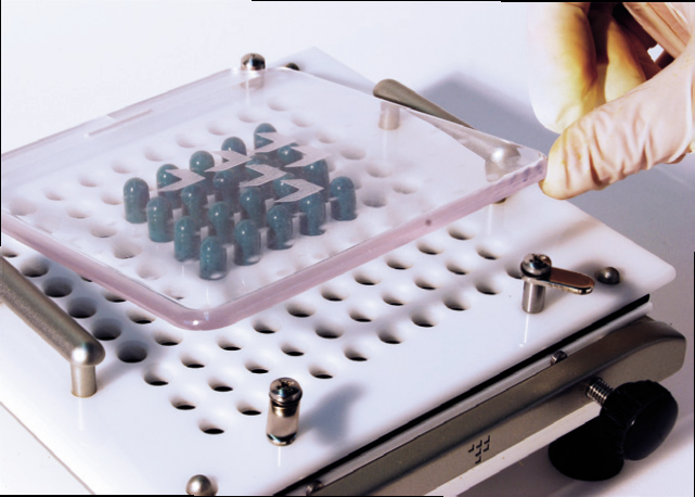 a hand holding a plastic tray with blue capsules