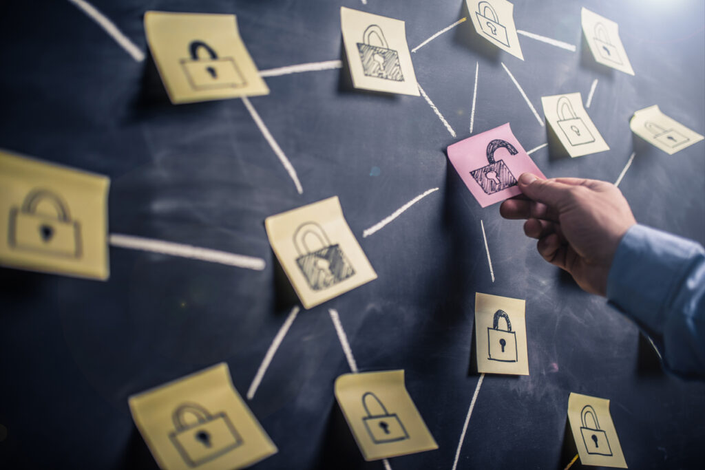 a hand holding a pink paper padlock on a blackboard