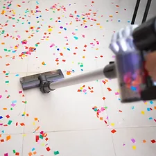 a person vacuuming the floor with confetti