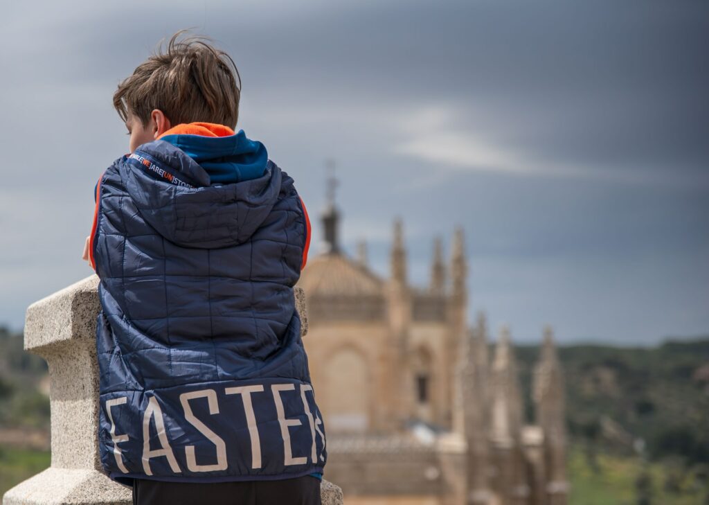 a boy in a vest leaning on a wall