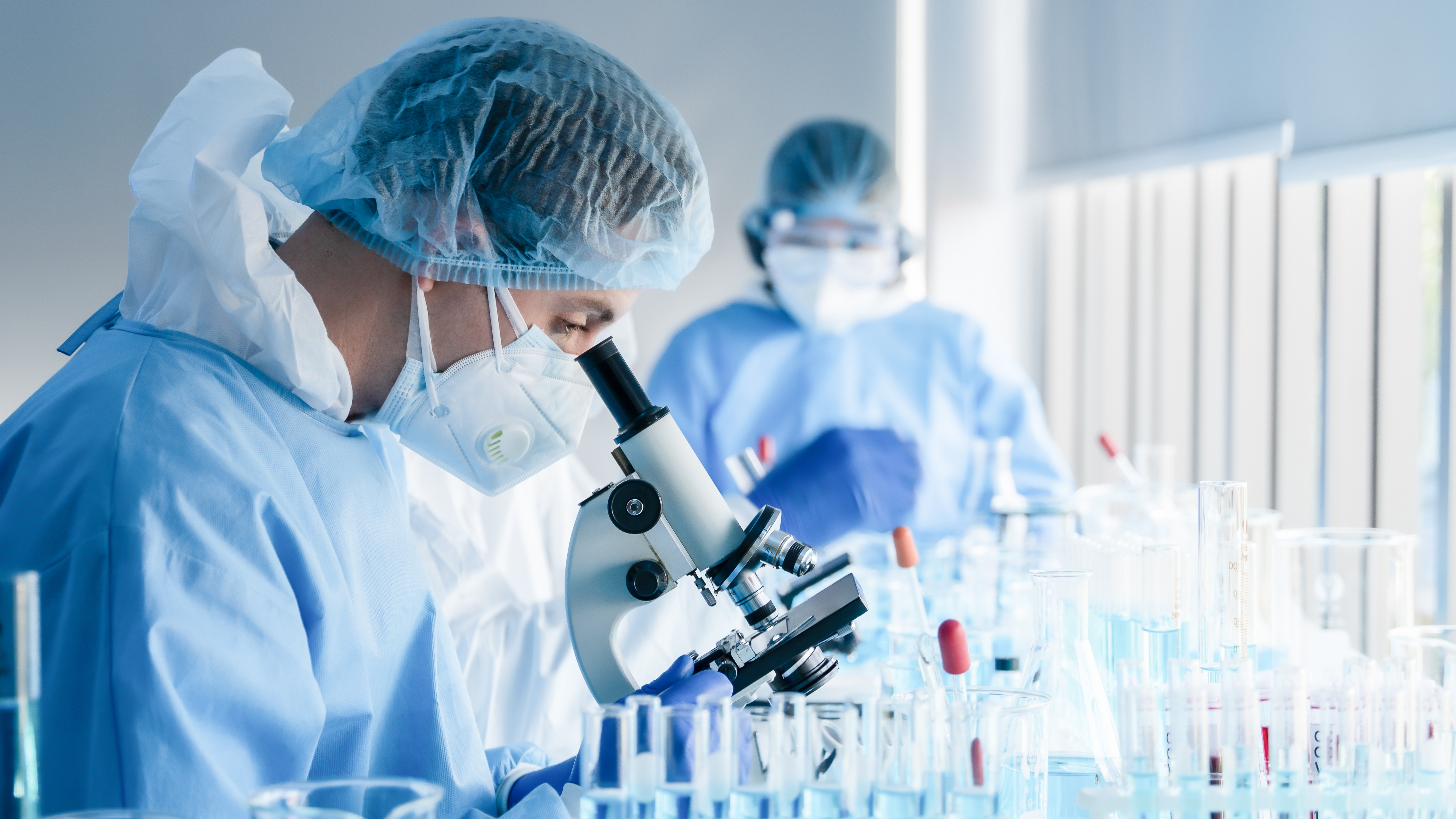 a group of people in protective gear looking through a microscope