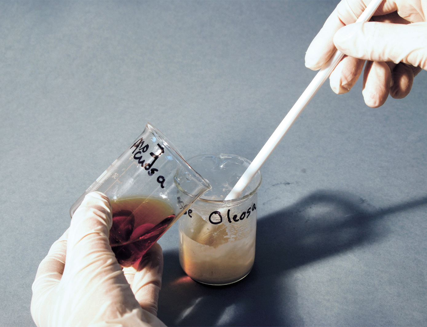 a hand holding a beaker with a white object in the middle