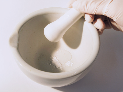 a hand holding a mortar and pestle