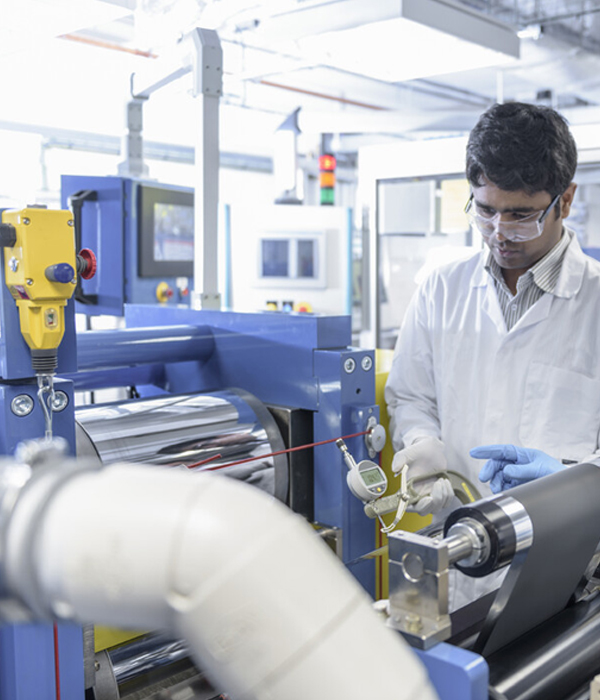 a man in a white coat and goggles working in a factory