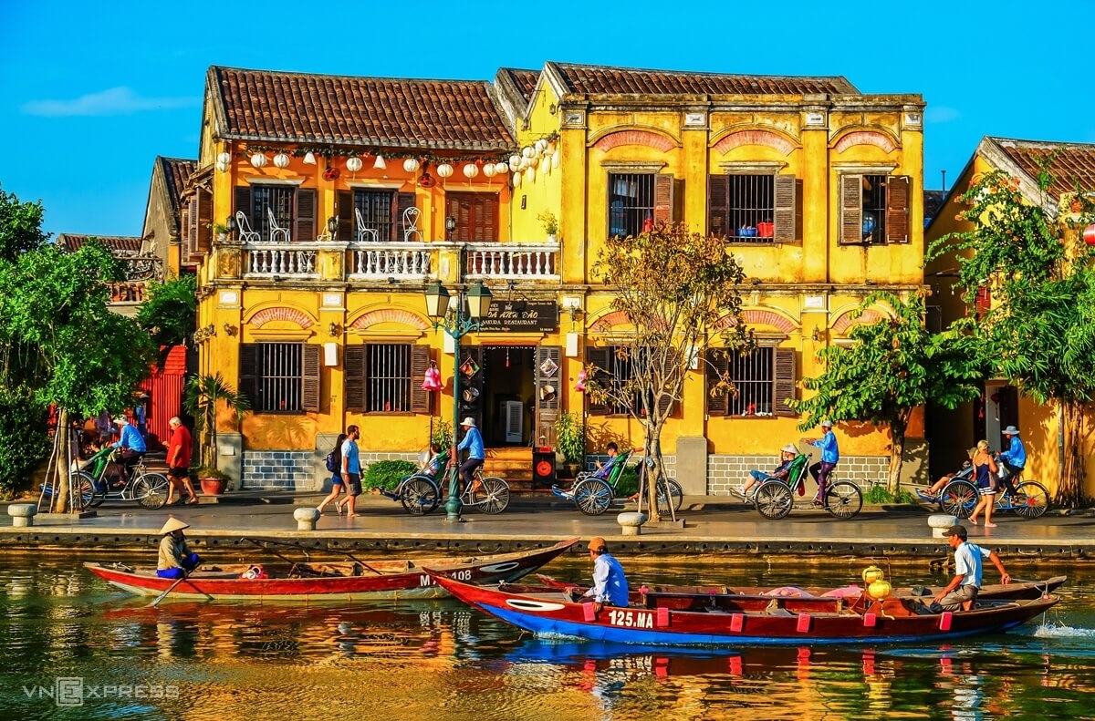 a group of people on a river with boats in front of a yellow building