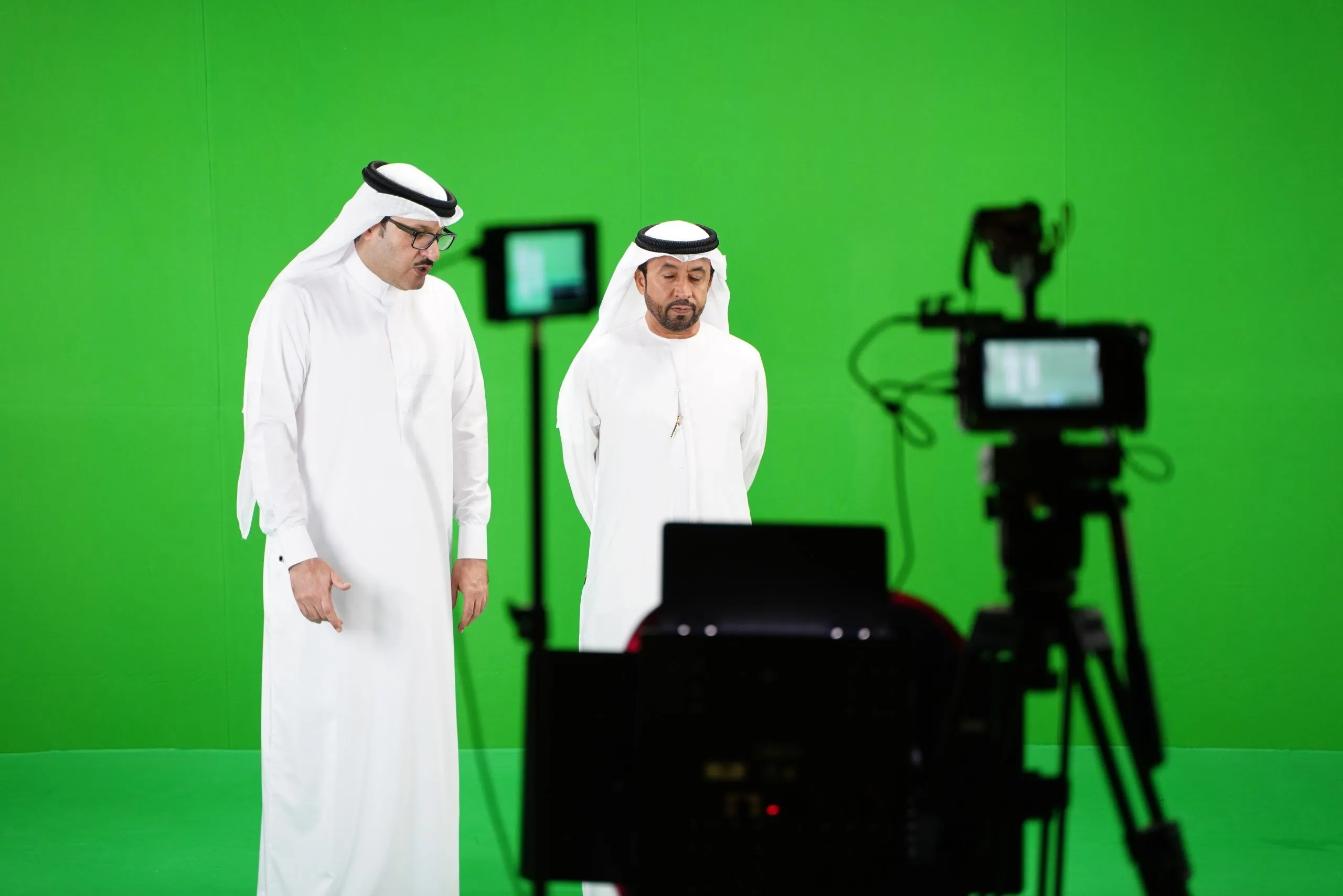 two men in white robes in front of a green screen