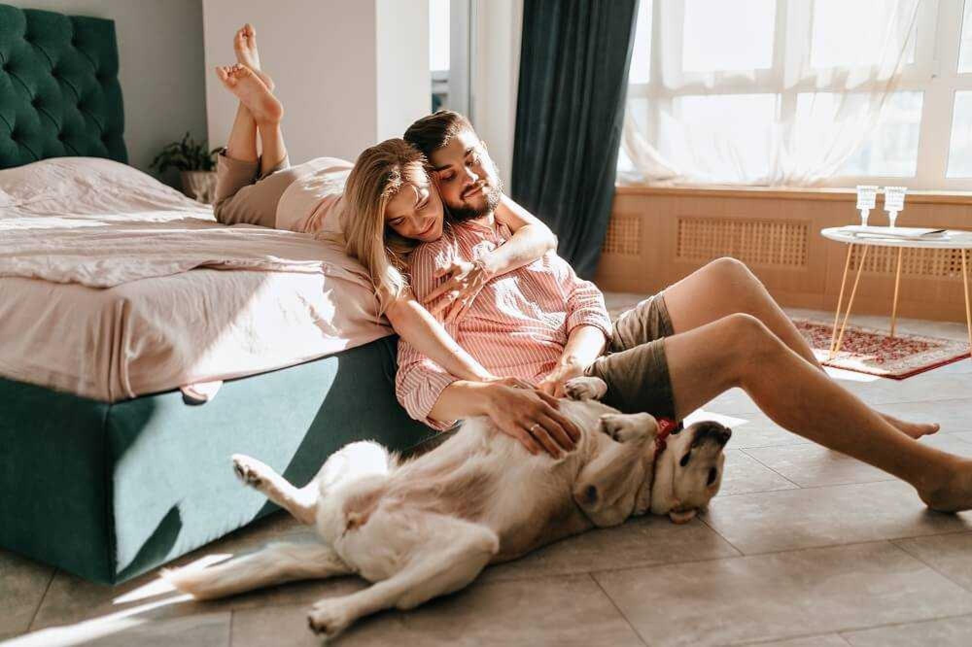 a man and woman lying on a bed with a dog