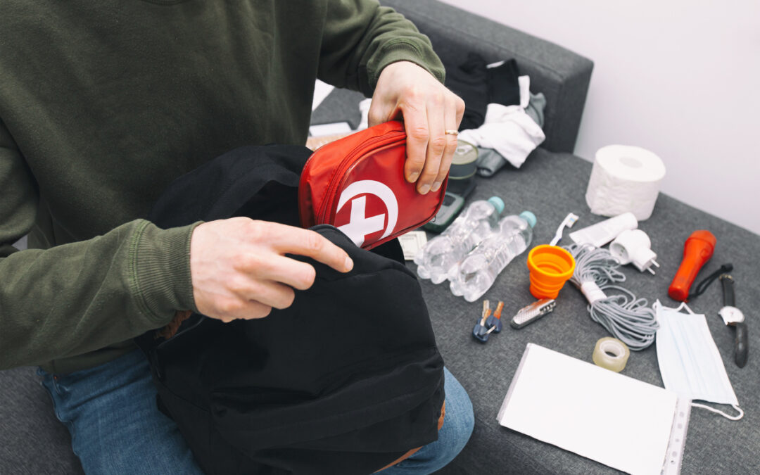 a person putting a first aid kit in a backpack