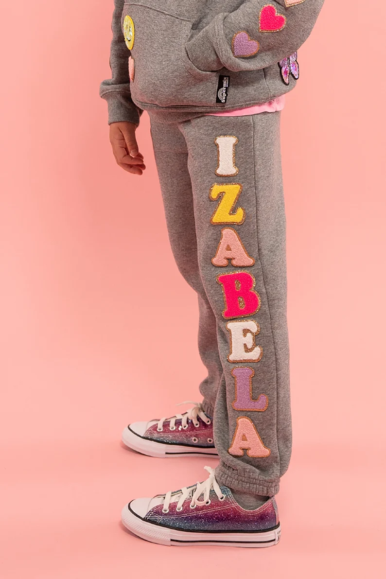 a person wearing grey sweatpants with colorful letters on them