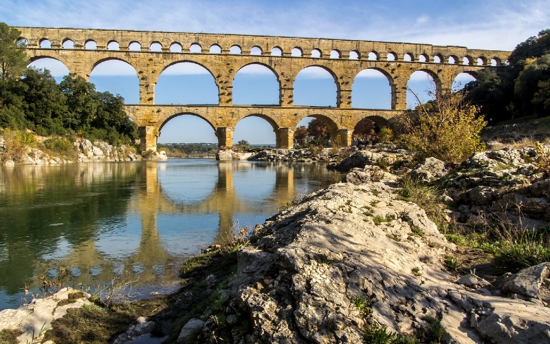 a stone bridge over water with Pont du Gard in the background