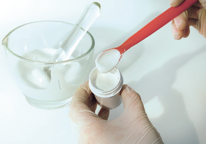 a hand holding a red spoon over a container