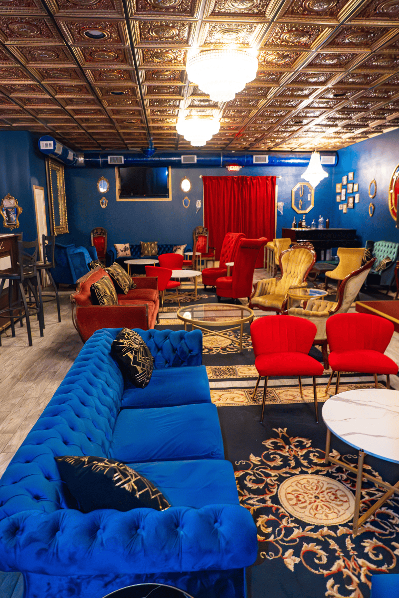 a room with a blue wall and red couches and tables