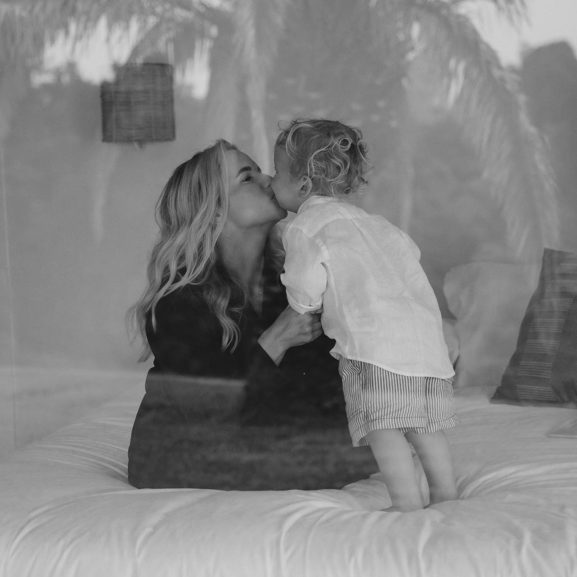 a woman kissing a child on a bed
