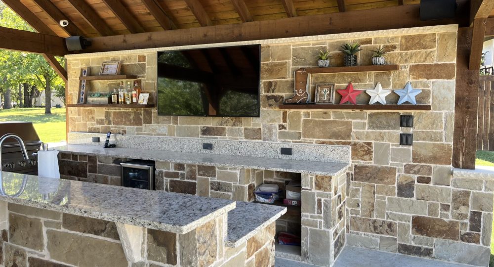 a stone patio with a television and bar counter