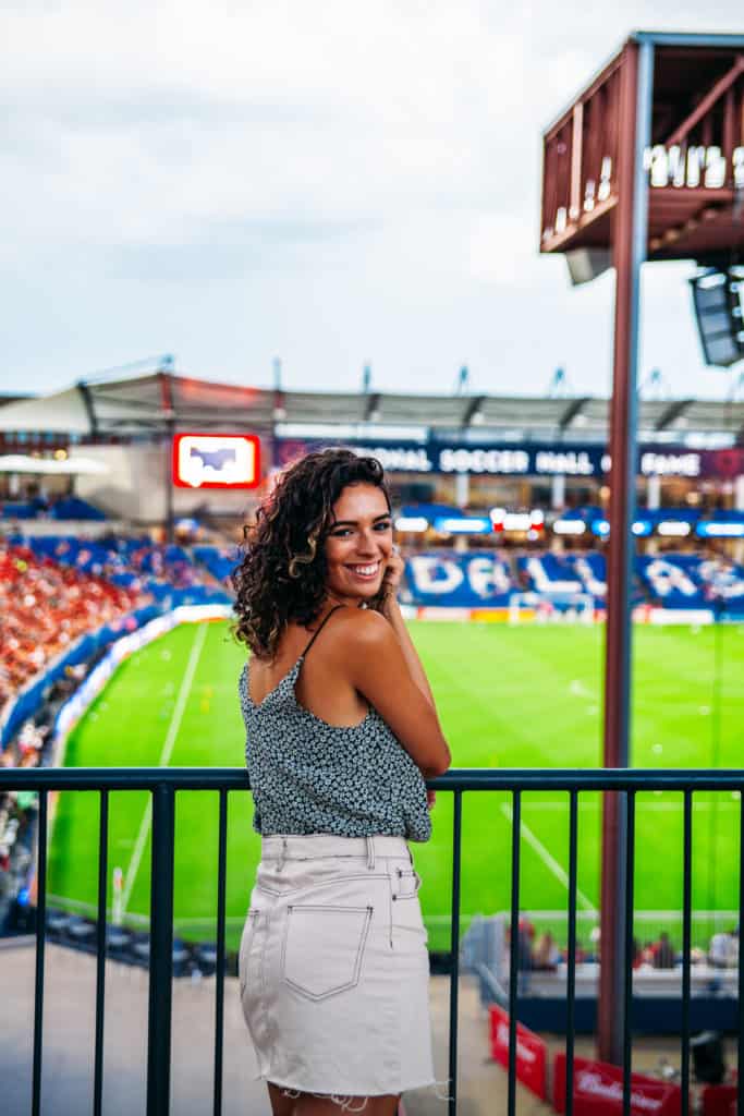 a woman leaning on a railing in front of a football field