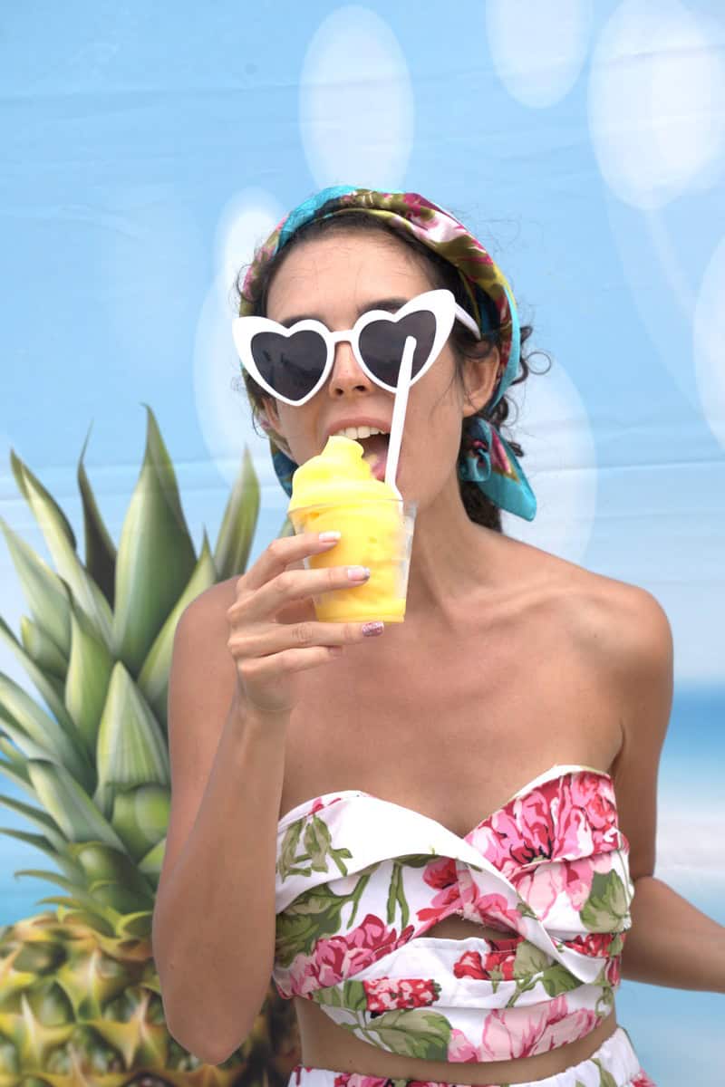 a woman wearing sunglasses and holding a yellow drink