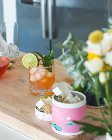 a glass of iced tea with lime slices and mint leaves on a table