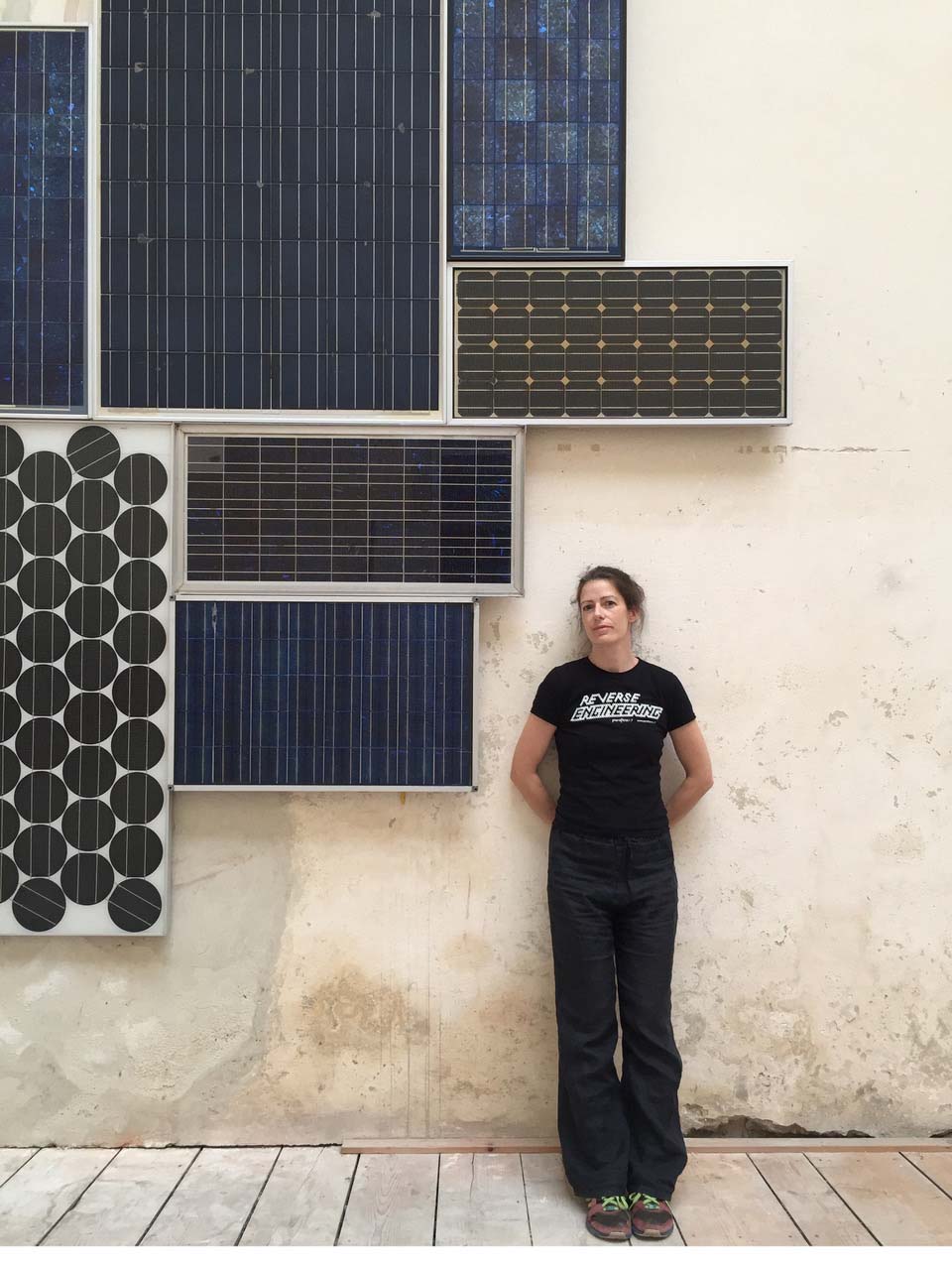 a woman standing next to a wall with solar panels