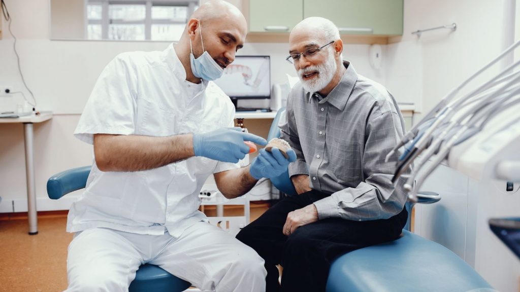 a man sitting in a chair with a dentist in his office