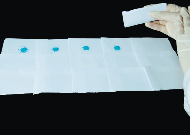 a hand holding a piece of paper with blue spots