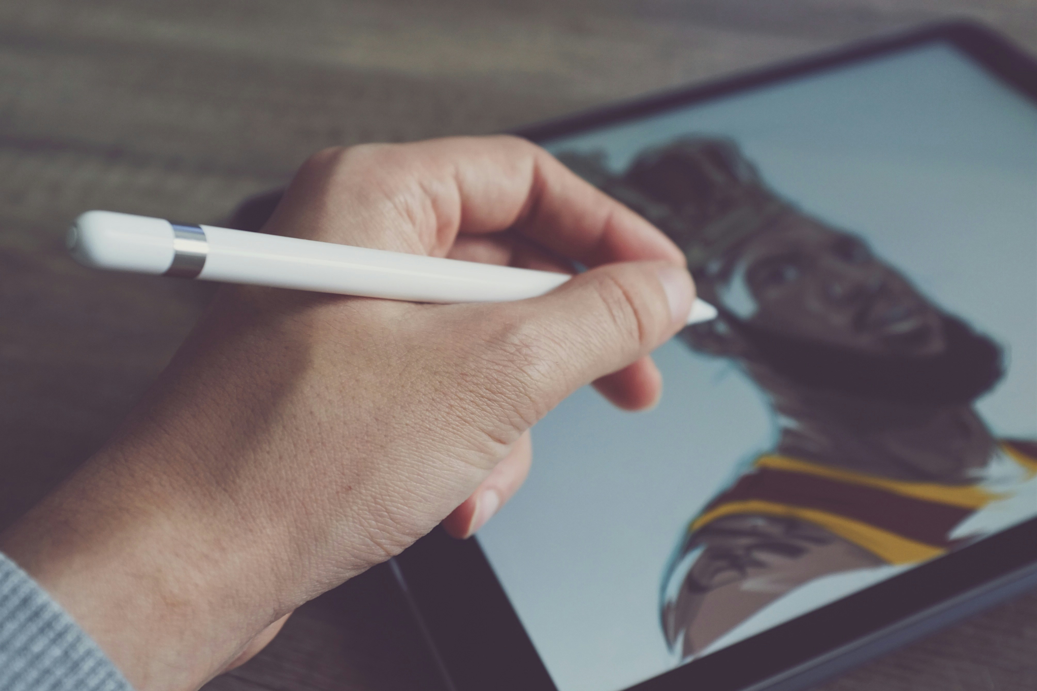 a hand holding a stylus on a tablet