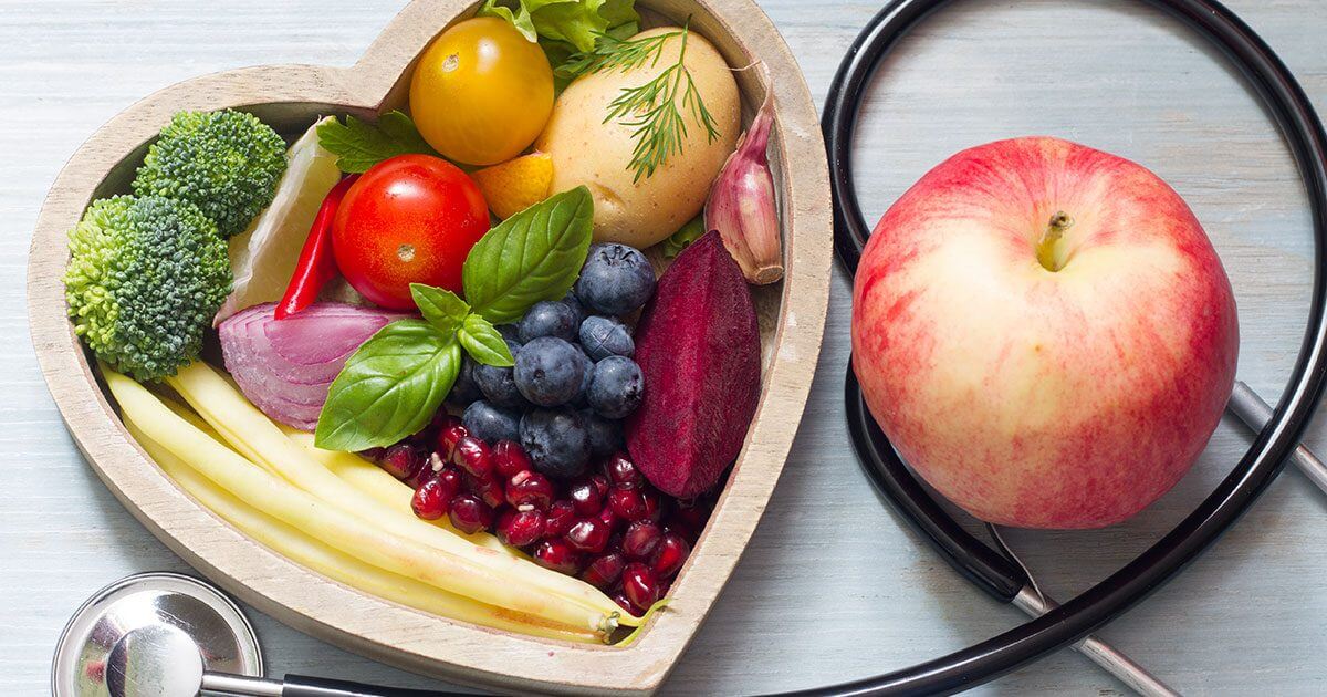 a heart shaped bowl with fruits and vegetables next to a stethoscope